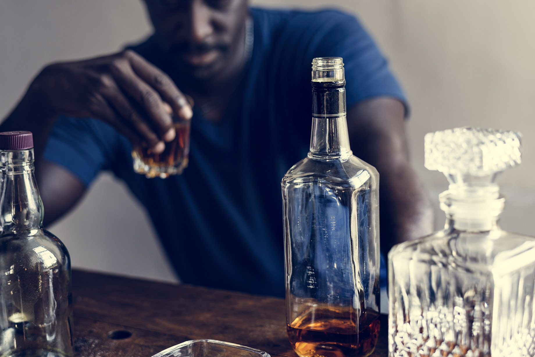 African descent man sitting drinking whiskey alcoholic addiction bad habit